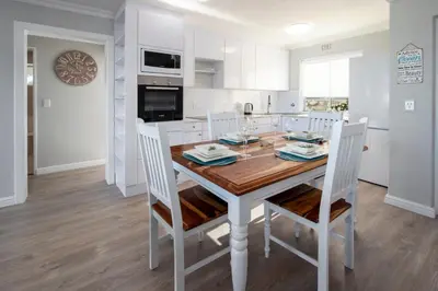 a kitchen and dining room with a wooden table and chairs at 29@Whale Rock Estate in Hermanus