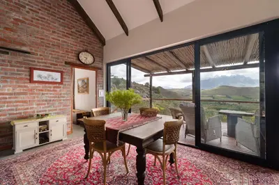 a dining room with a table and a large window at Fynbosrust in Wolseley