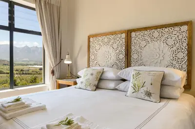 a bedroom with a white bed with a large window at Fynbosrust in Wolseley