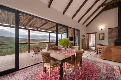 a dining room with a table and chairs and a large window at Fynbosrust in Wolseley