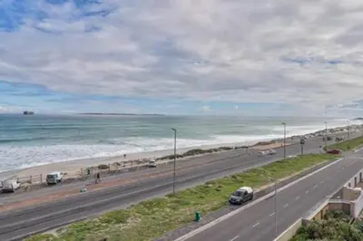 a road next to the beach with cars on it at Ocean View C403 by CTHA in Bloubergstrand