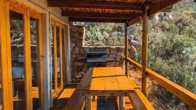 a porch of a cabin with a bench and a grill at Stonewood Mountain Cabin in Breerivier