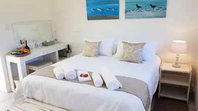 a bedroom with a large white bed with towels on it at 57 on Vermont in Hermanus