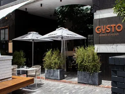 two tables and umbrellas in front of a building at Century City Hotel Bridgewater in Cape Town