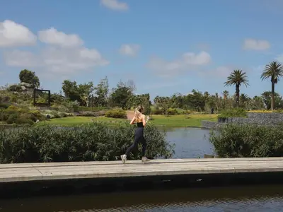a woman walking on a walkway near a body of water at Century City Hotel Bridgewater in Cape Town