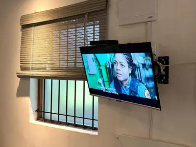 a flat screen tv hanging on a wall next to a window at Open Room Comfort in Cape Town