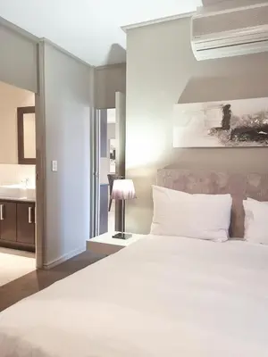 a bedroom with a large white bed and a sink at Manhattan by Smart City Stays in Cape Town