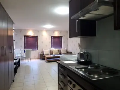 a kitchen and living room with a couch and a table at Manhattan by Smart City Stays in Cape Town