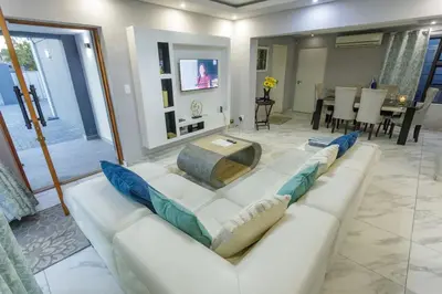 a living room with a white couch with blue pillows at Cozier Glitz in Cape Town