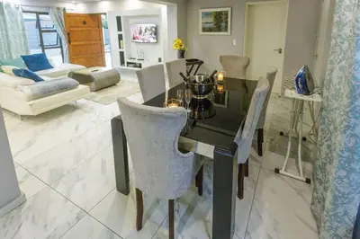a dining table and chairs in a living room at Cozier Glitz in Cape Town