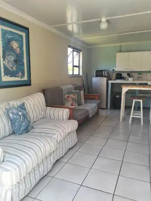 a living room with a couch and a kitchen at Its Practical Holidays in Hermanus