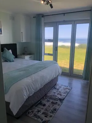 a bedroom with a bed with a view of the ocean at Hermanus Beach Club - St Tides House 19 in Hermanus
