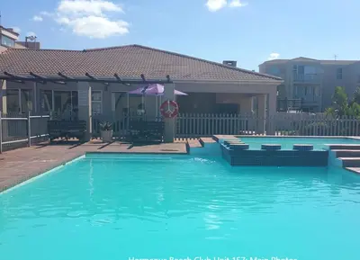 a large blue swimming pool in front of a house at Hermanus Beach Club - St Tides House 19 in Hermanus
