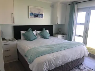 a bedroom with a large bed with blue pillows at Hermanus Beach Club - St Tides House 19 in Hermanus