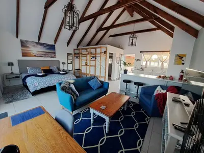 a living room with a blue couch and a bed at Cape Dutch Flair in Durbanville