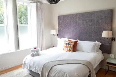 a bedroom with a large bed with white sheets and pillows at Macaron Boutique Guest House in Franschhoek