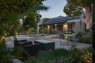 a patio with tables and chairs in front of a building at Macaron Boutique Guest House in Franschhoek