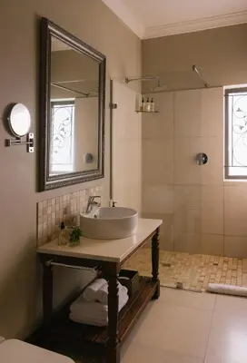 a bathroom with a sink and a shower with a mirror at Under Oaks Guesthouse in Paarl