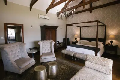 a bedroom with a large bed and two chairs at Under Oaks Guesthouse in Paarl