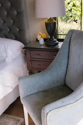 a bedroom with a bed and a chair next to a nightstand at Under Oaks Guesthouse in Paarl
