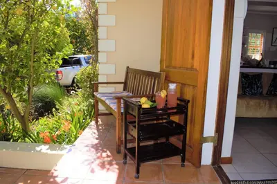 a porch with a wooden chair and a table at Smith Cottage in Franschhoek
