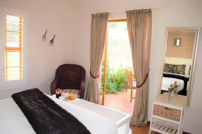 a bedroom with a bed and a chair and a window at Smith Cottage in Franschhoek