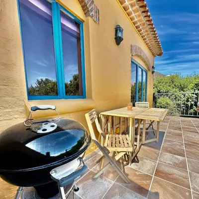 a room with a grill and a table on a patio at Sunset Beach holiday accommodation in Cape Town