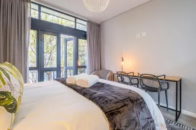 a bedroom with a bed and a large window at Lemon Rind - 16 Eikehoff in Stellenbosch