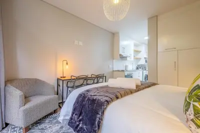 a bedroom with a bed and a chair at Lemon Rind - 16 Eikehoff in Stellenbosch