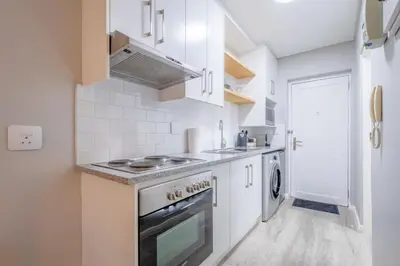 a kitchen with white cabinets and a stove top oven at Lemon Rind - 16 Eikehoff in Stellenbosch