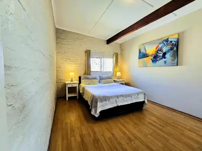 a bedroom with a bed and a painting on the wall at Walters Lane Deluxe Garden Apartment 3 - No loadshedding in Cape Town