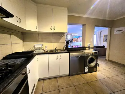 a kitchen with a sink and a washing machine at Walters Lane Deluxe Garden Apartment 3 - No loadshedding in Cape Town