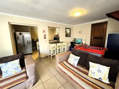 a living room with two couches and a kitchen at Walters Lane Deluxe Garden Apartment 3 - No loadshedding in Cape Town