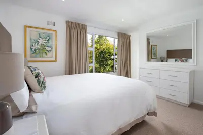 a white bedroom with a large bed and a window at Birdsong in Hermanus