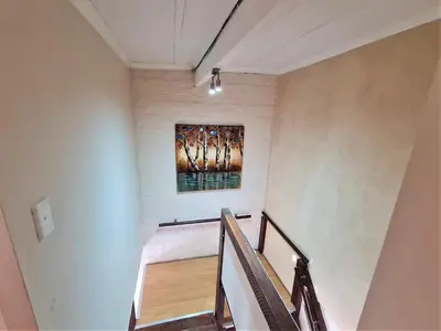 a staircase in a house with a painting on the wall at Walters Lane Comfort Apartment 2 - No Loadshedding in Cape Town