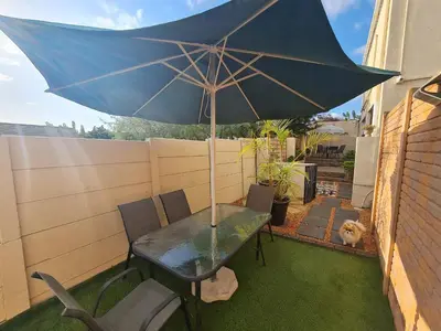 a table with an umbrella on a patio at Walters Lane Comfort Apartment 2 - No Loadshedding in Cape Town