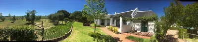 a white house with a fence next to a field at Mooi Bly in Paarl