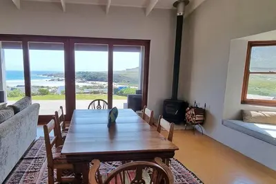 a living room with a wooden table and a fireplace at Hilltop Heaven, Walk to beach, Pool, Ocean & River views in Pringle Bay