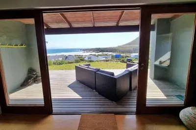 a door to a balcony with a view of the ocean at Hilltop Heaven, Walk to beach, Pool, Ocean & River views in Pringle Bay