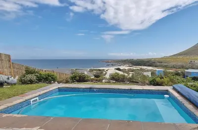 a swimming pool with a view of the ocean at Hilltop Heaven, Walk to beach, Pool, Ocean & River views in Pringle Bay