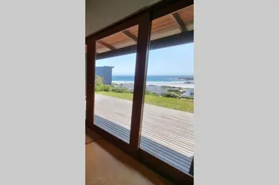 a room with a window with a view of the ocean at Hilltop Heaven, Walk to beach, Pool, Ocean & River views in Pringle Bay