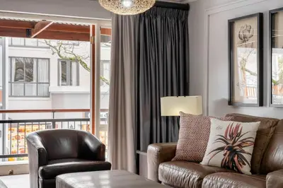 a living room with a leather couch and a chair at Avemore Jan Cats No 5 full backup power in Stellenbosch