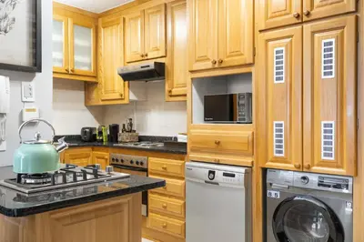 a kitchen with wooden cabinets and a tea kettle on a stove at Avemore Jan Cats No 5 full backup power in Stellenbosch