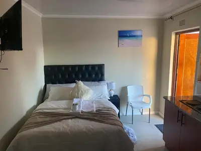 a bedroom with a large bed and a chair at SABATH LODGE in Cape Town