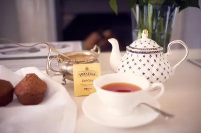 a cup of tea and a tea pot and muffins on a table at Corner House Residence in Franschhoek
