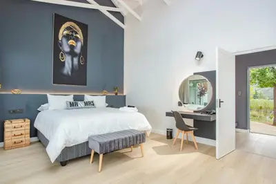 a bedroom with a bed and a desk and a mirror at Droom Guesthouse in Franschhoek