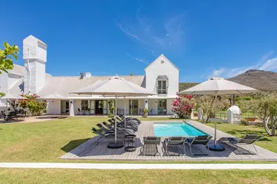 a house with a pool and chairs and umbrellas at Droom Guesthouse in Franschhoek