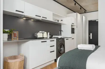 a kitchen with white cabinets and a washing machine at Bridgewater One Apartments in Cape Town