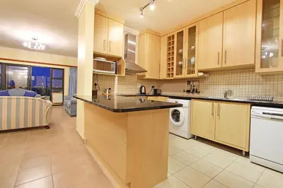 a kitchen with wooden cabinets and a dishwasher at Knightsbridge 407 by Host Agents in Cape Town