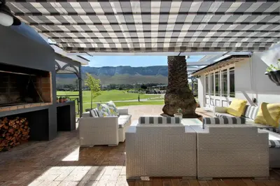 an outdoor patio with couches and a fireplace at 19th Hole Guest Lodge - Golfers paradise in Hermanus